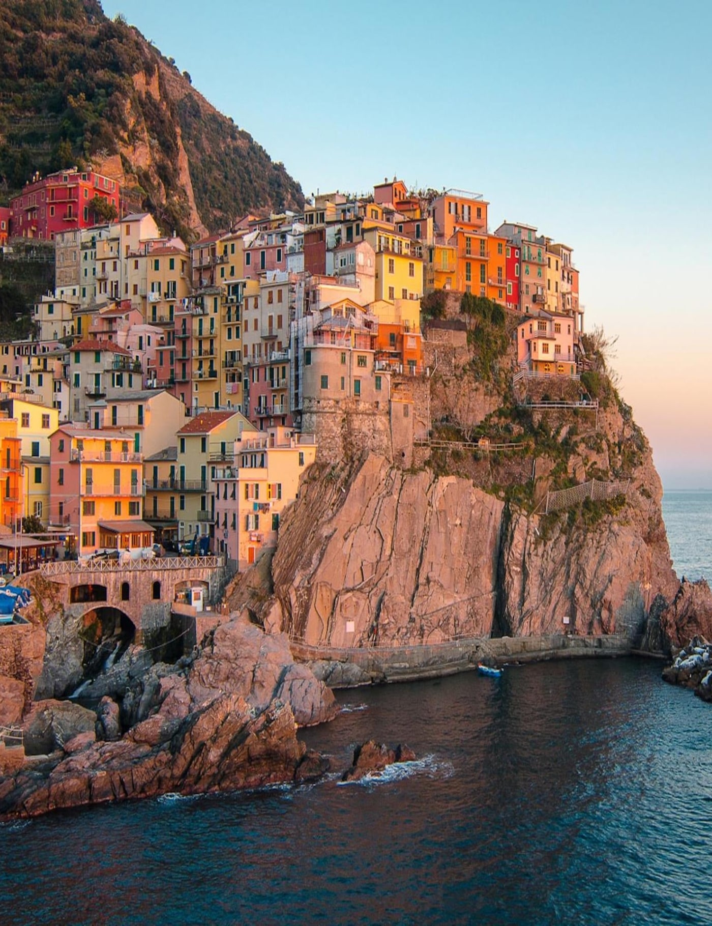 Blick über die terrassierte Steilküste der Cinque Terre mit einem farbigen Dorf über dem Meer